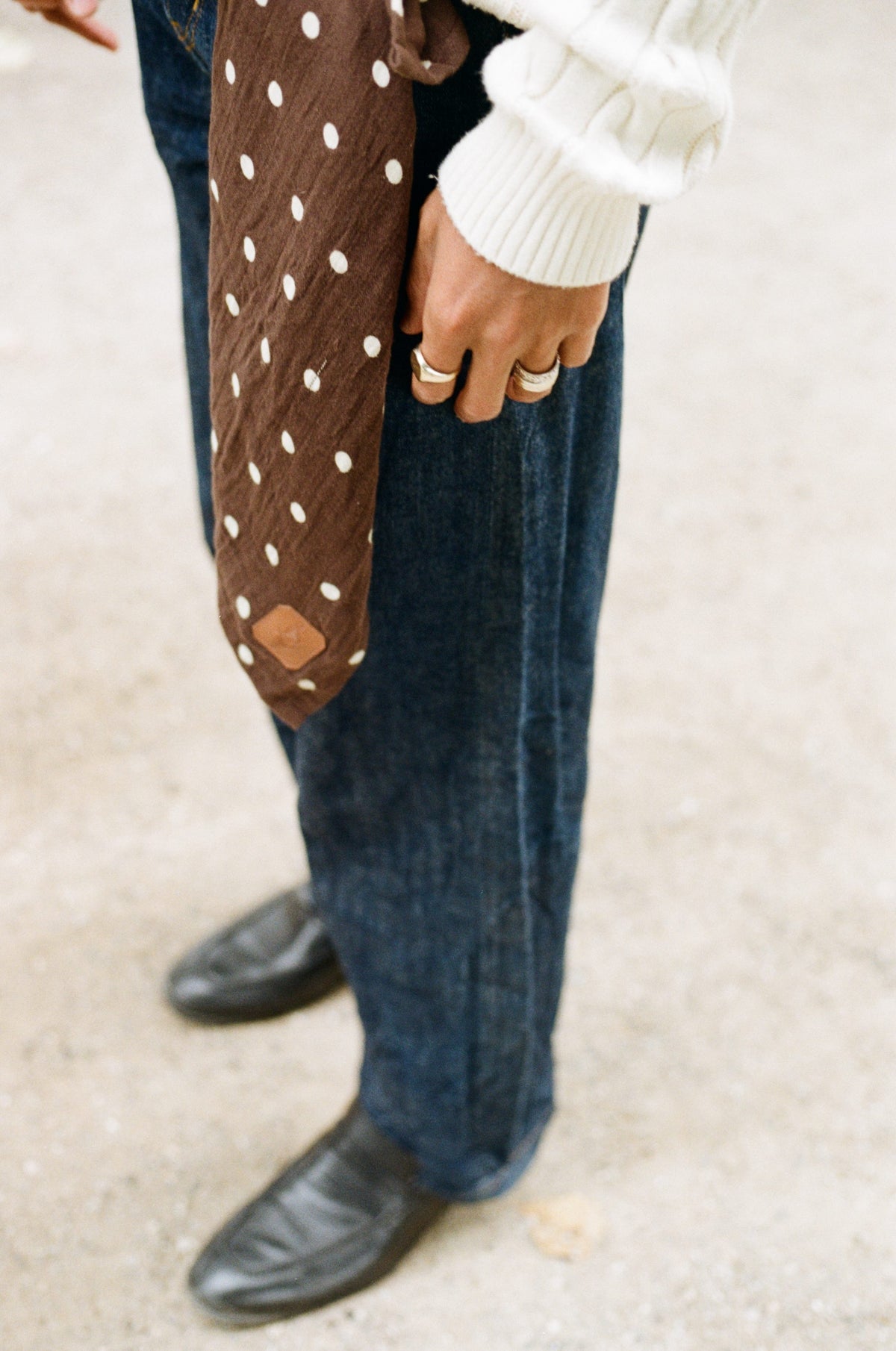 A Pierrot Dot Salomë muslin cloth held at the hip against dark denim on a Copenhagen pavement.